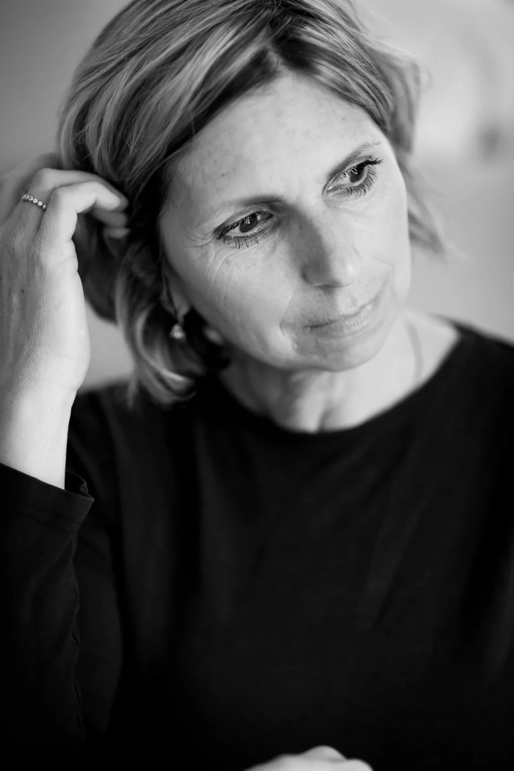 Portrait von Achtsamkeitstrainerin für Frauen, Alexandra Wittek. Alex Wittek blickt bedeutungsvoll aus dem Bild heraus nach unten und streicht sich nachdenklich durchs Haar.